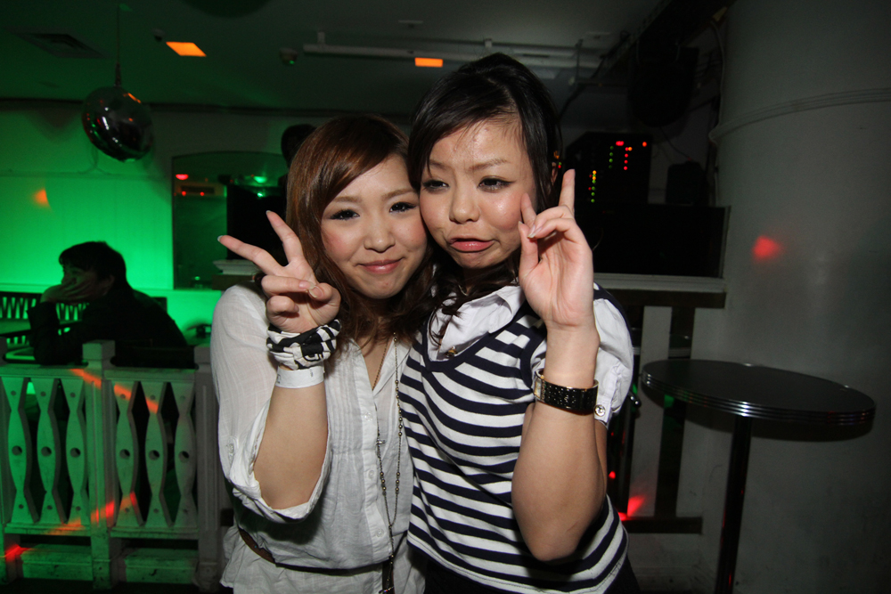 two asian woman standing next to each other making the v sign