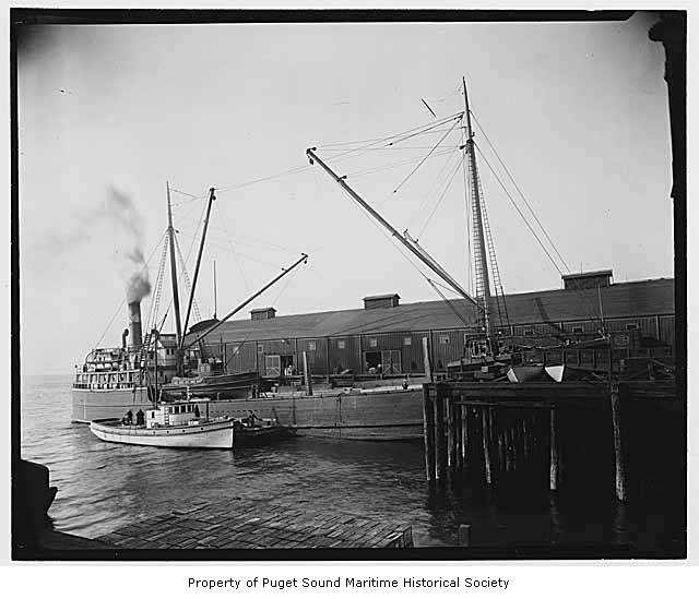 an old black and white po with tug boats near dock