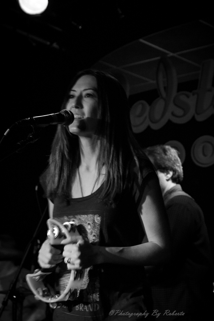 a woman with long hair holding a wii remote playing a game at a club