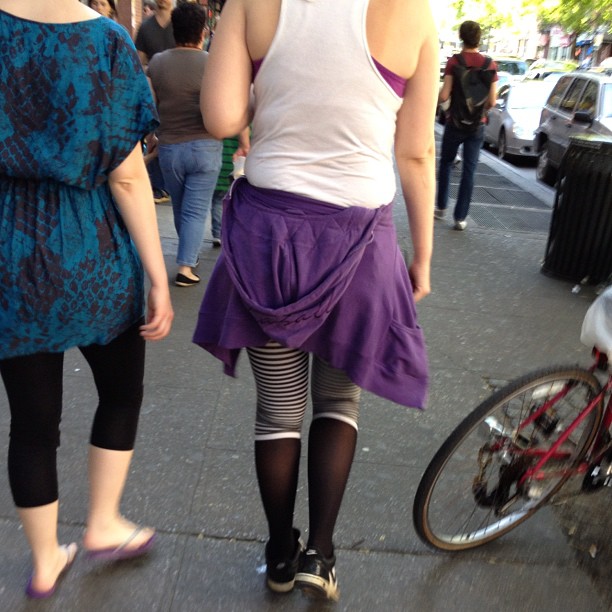 two girls walking down a sidewalk with legs wearing garters