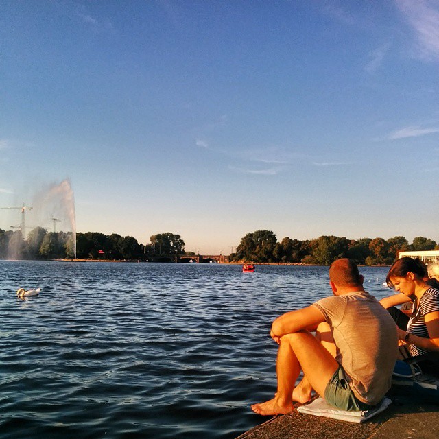 two people sitting on a concrete platform at the water's edge