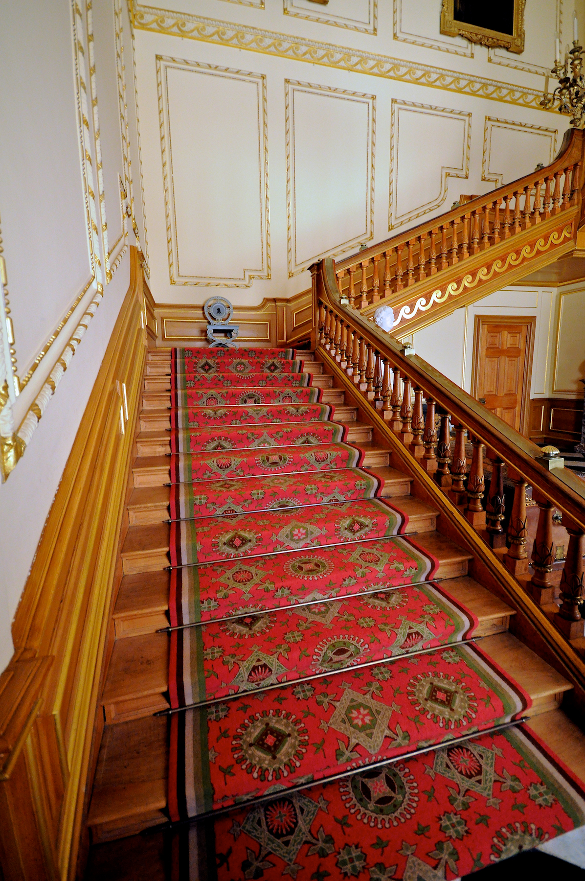 stairs with red carpet and ornate railings in a large house