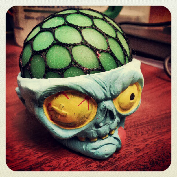 a blue skull statue with a green in wearing a netted ball head cover