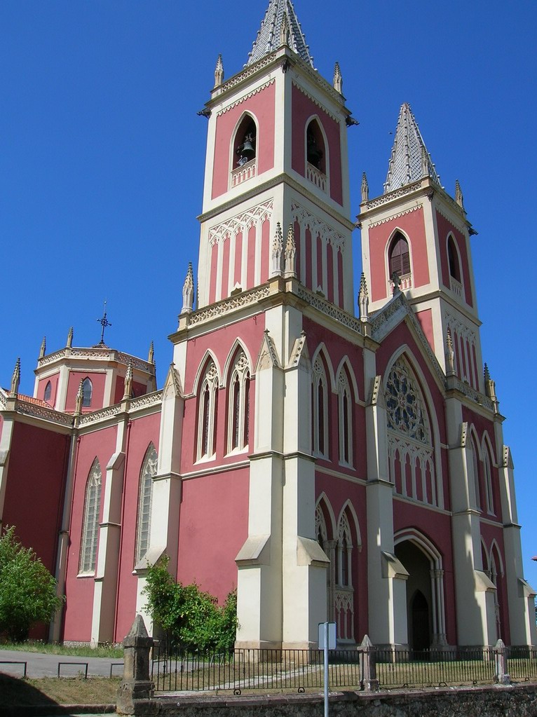large pink building that has two steeple at top and a clock in the middle