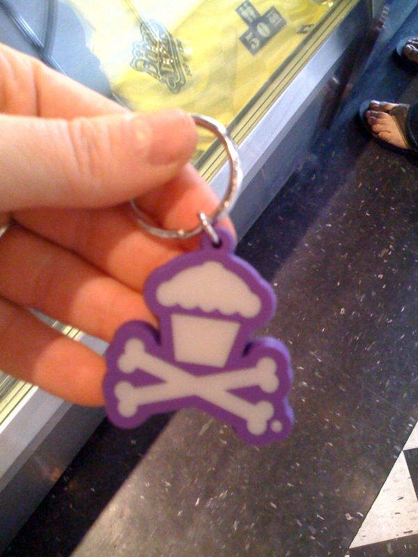 someone is holding a small key chain with a skull in the shape of a shirt on it