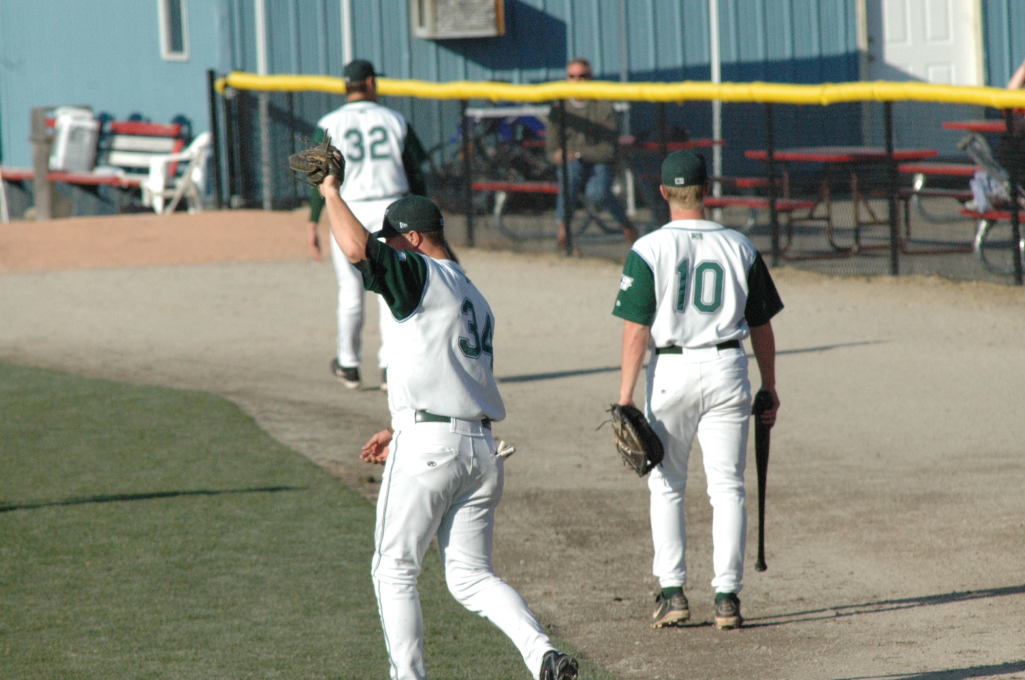 baseball players in white uniforms are walking across a field