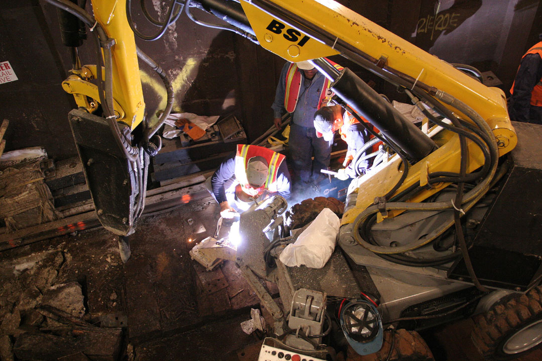 workers are seen at work as a machine is working on a project