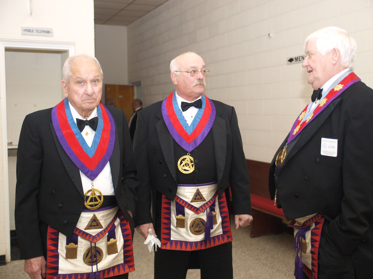 three men standing and wearing their uniforms with ties