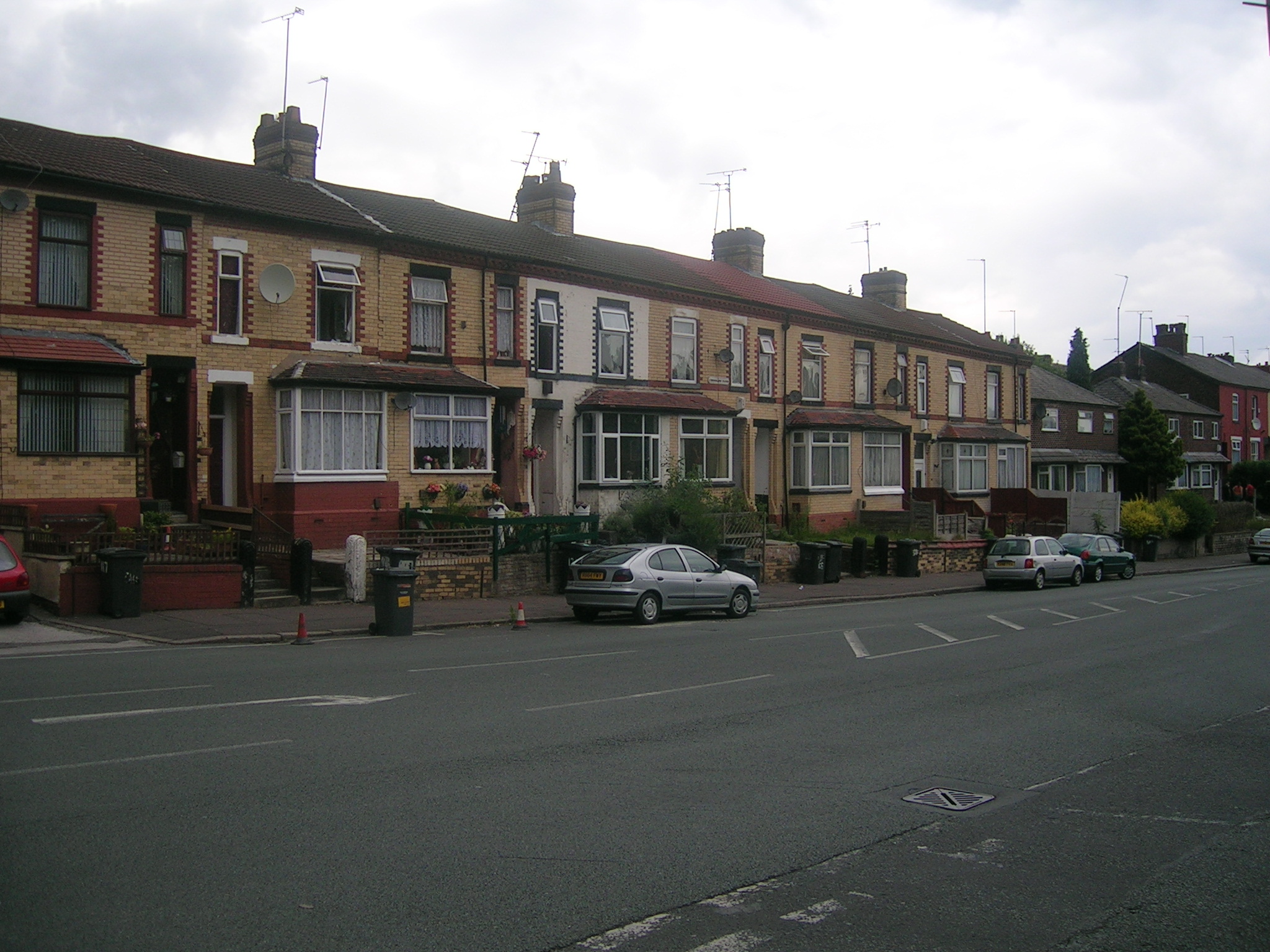 a street scene with parked cars next to some brown brick houses