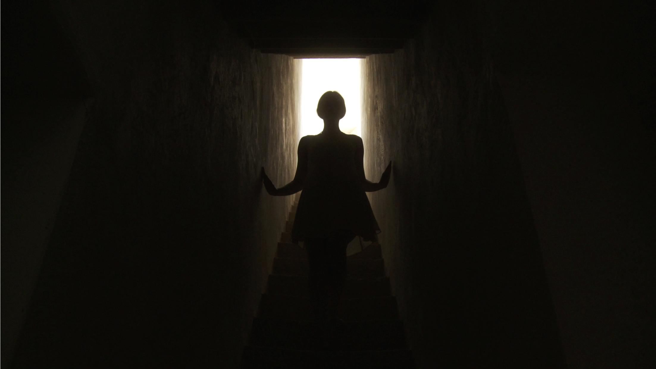 a woman in a dark hallway holding her hands up
