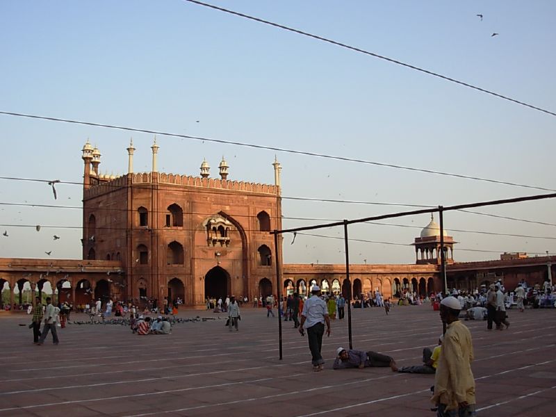 people walk around the plaza at the mosque