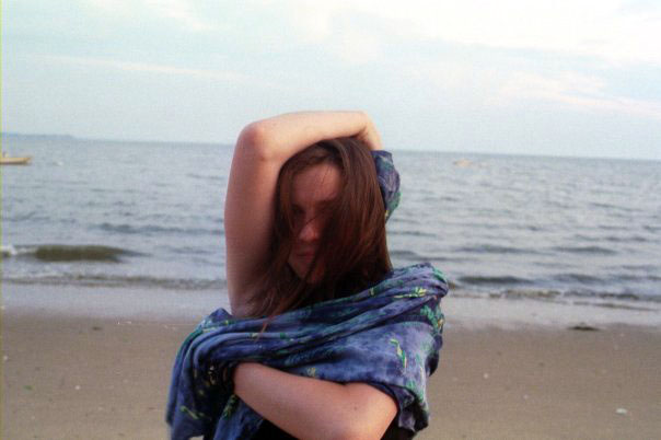 there is a woman with her hands in the hair standing at the beach