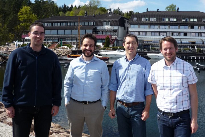 three men are standing near water while another man stands on the other side