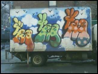 a truck covered in colorful graffiti driving down a street