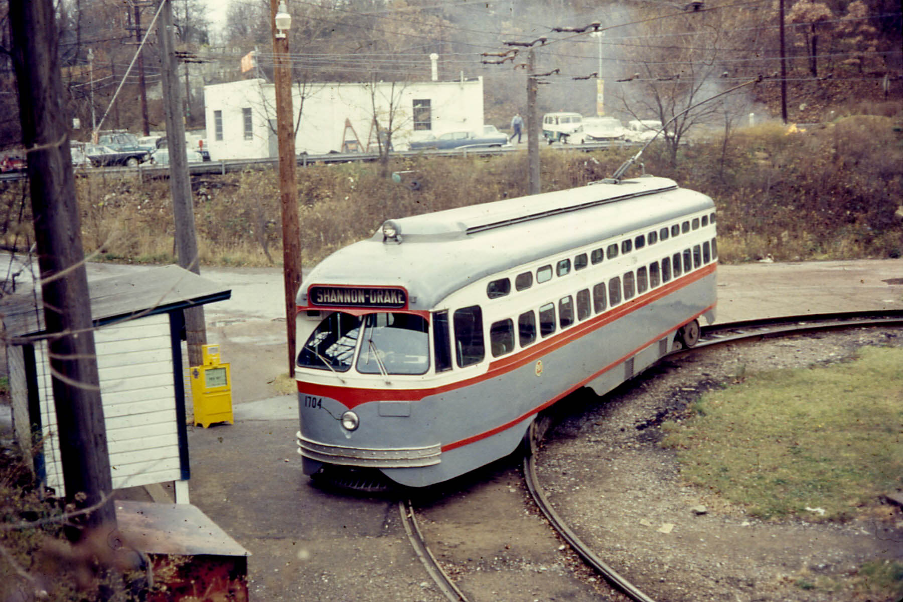 a gray and orange trolley going through an intersection