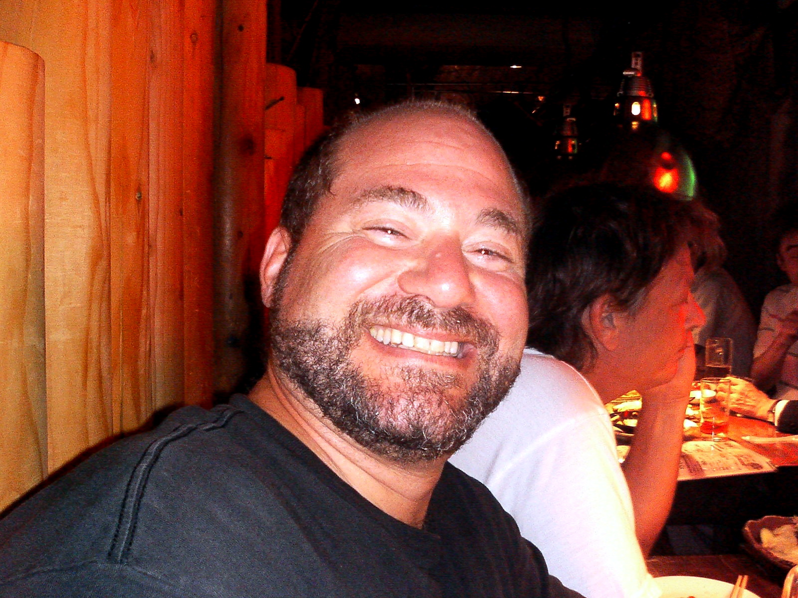 a smiling man with a goatee is sitting in a restaurant