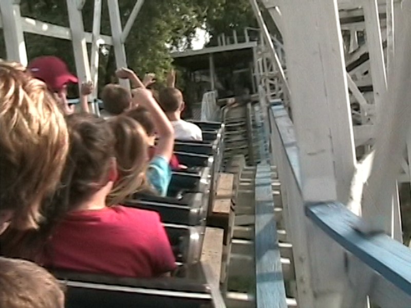 people at an amut park are watching as they ride the roller coaster