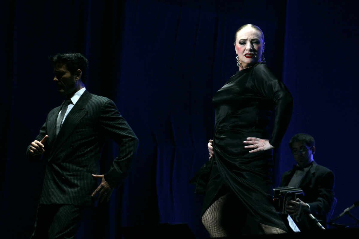 a woman is standing on stage in a black dress