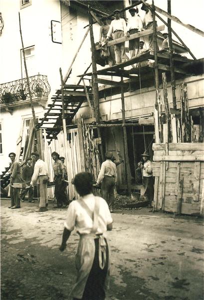 a black and white image of a man walking around a bunch of men in a construction yard