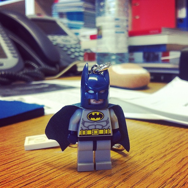 a small lego batman is standing on the desk