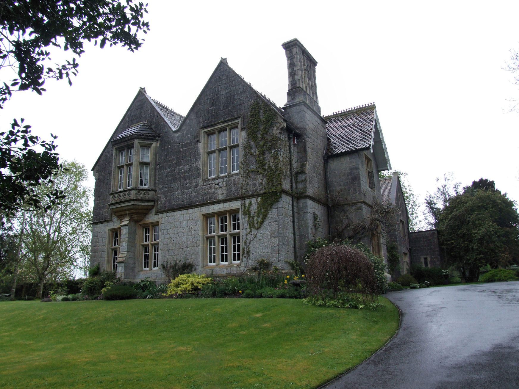 an old grey house with big windows in a lush green park