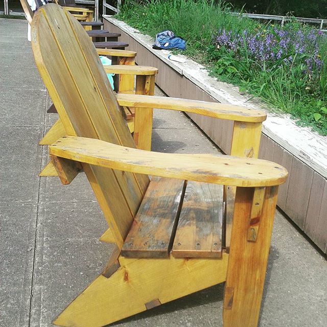 three wooden chairs sitting on top of a concrete sidewalk