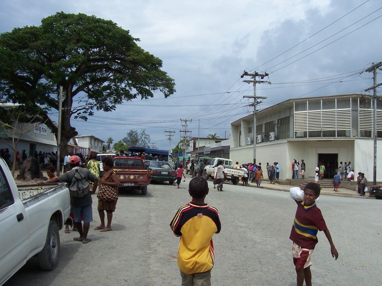 children walking on the street near many vehicles and trucks