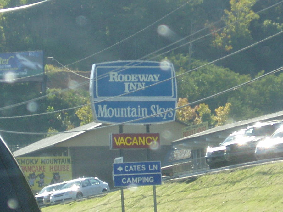 the view out a car window shows mountains and cars parked near a sign