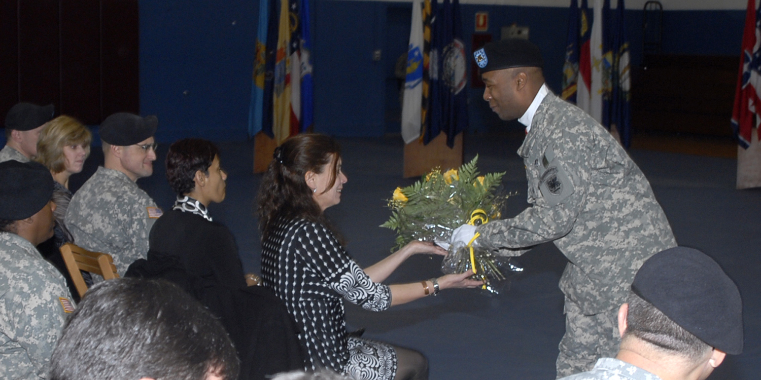 a man in uniform is handing flowers to another person in uniform