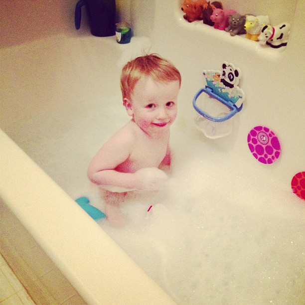 there is a baby sitting in the bathtub