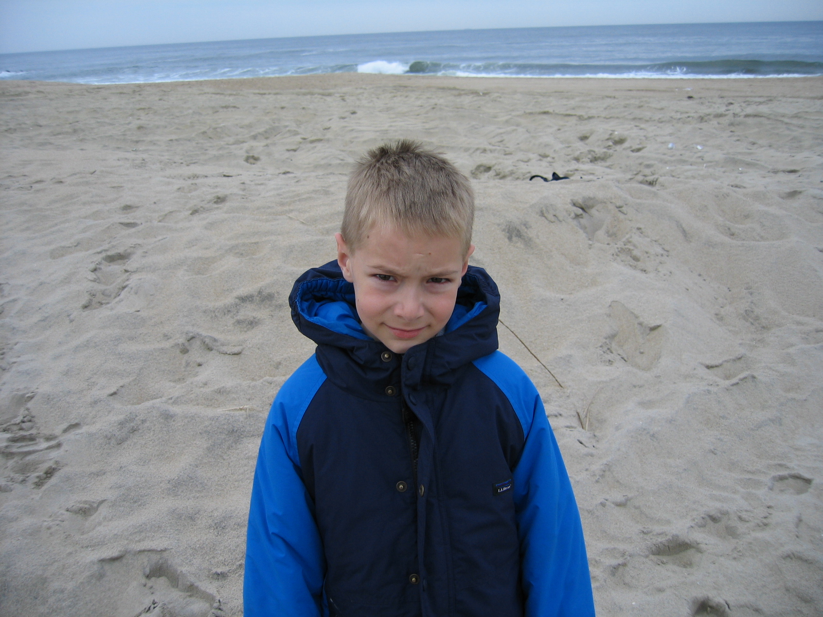 a little boy is on the beach in the sand