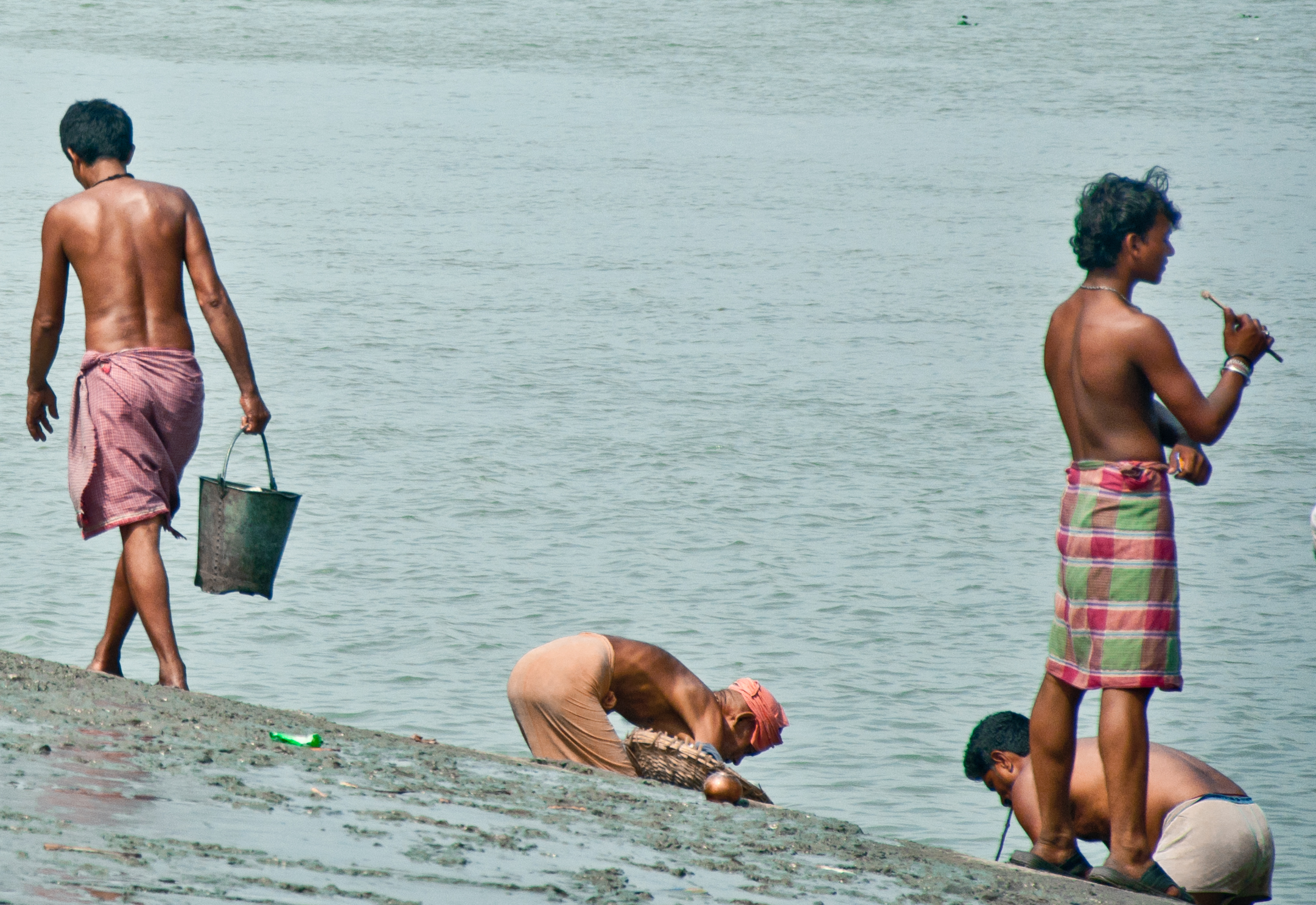 several boys are gathered around the side of a lake