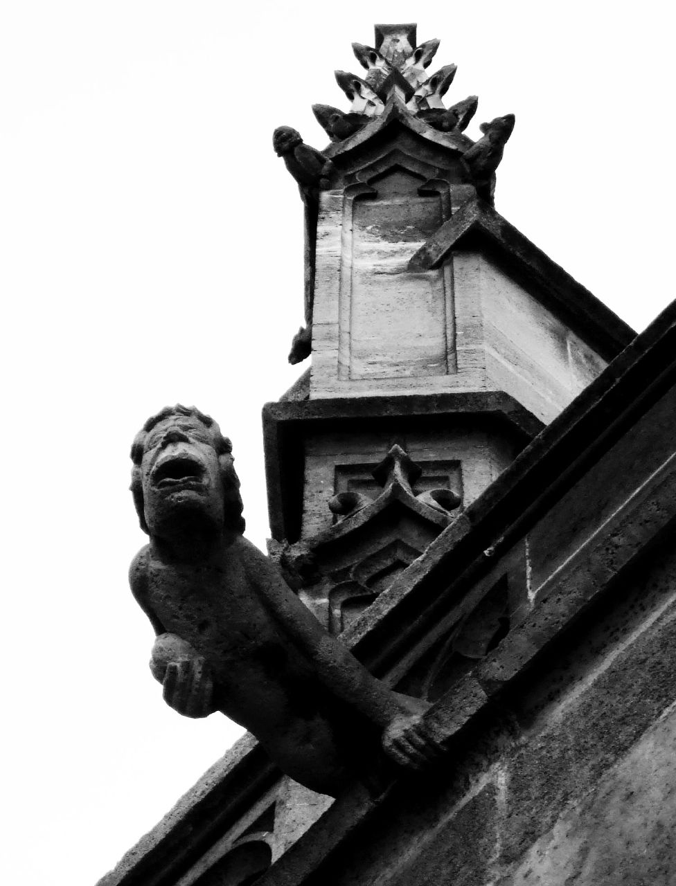 an artistic gargoyle decoration stands on the corner of an old building