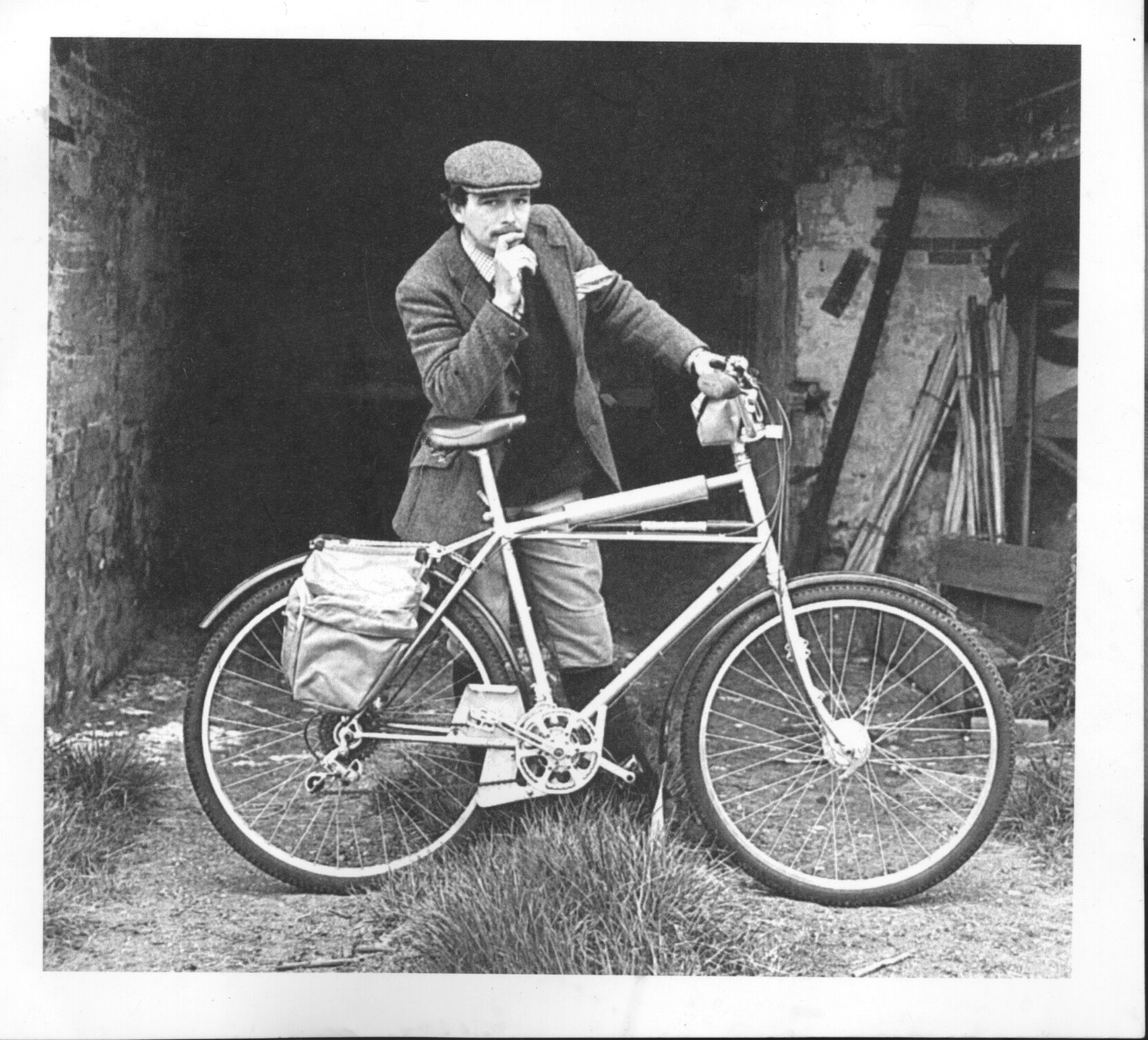 a man in a hat stands on his bicycle