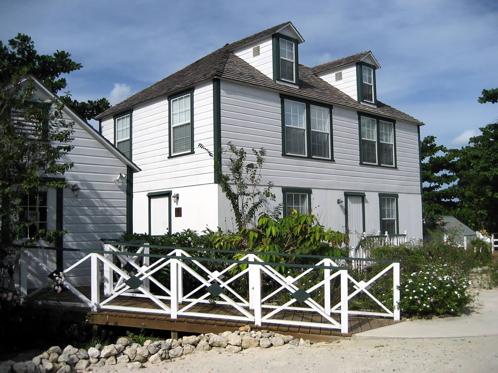 the back side of a three story white house with a wooden walkway leading to the front entrance