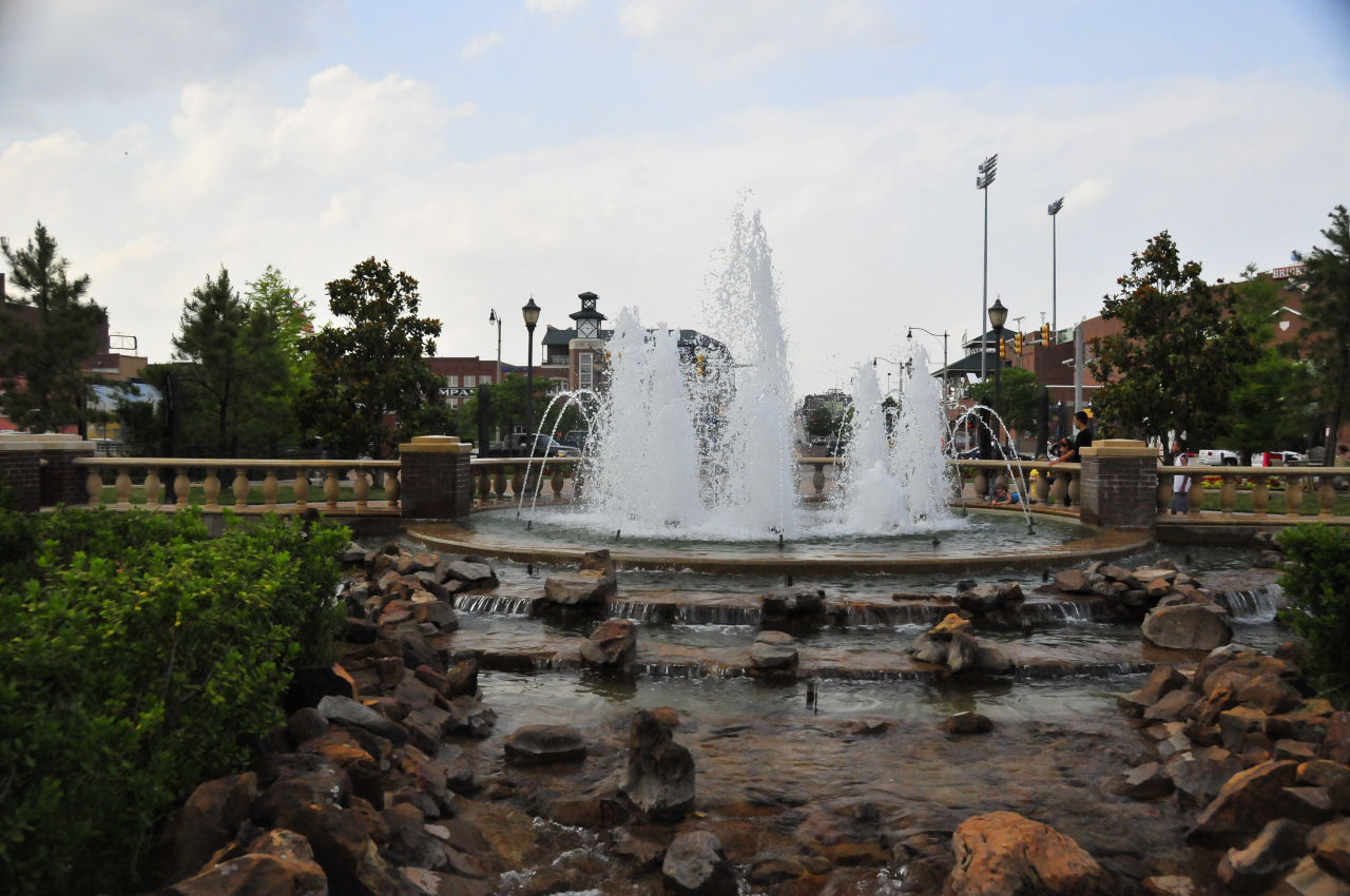 a large fountain in a park with rocks around it