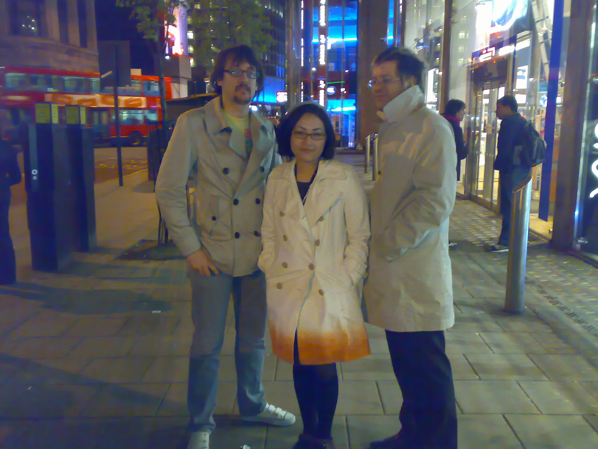 two men and a woman stand next to each other in a city