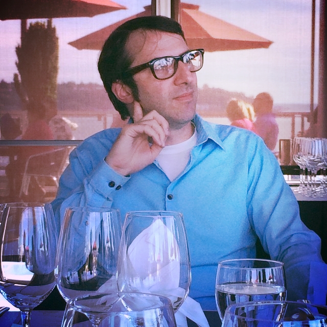 a man in glasses sitting at a table with glasses