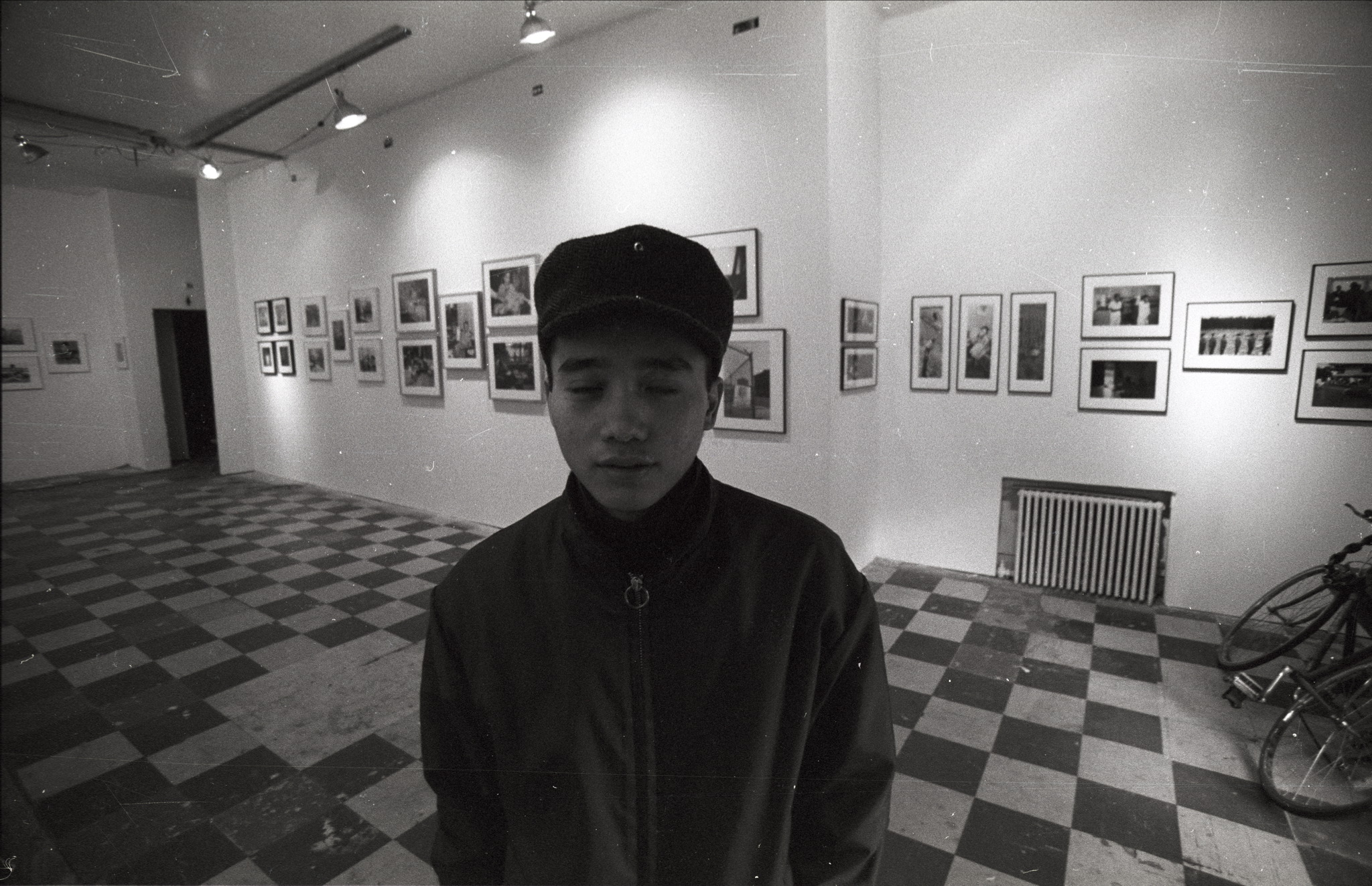 a young man stands in front of some portraits
