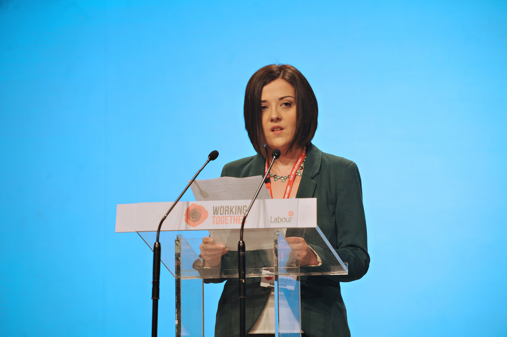 woman speaking at a podium in front of microphone