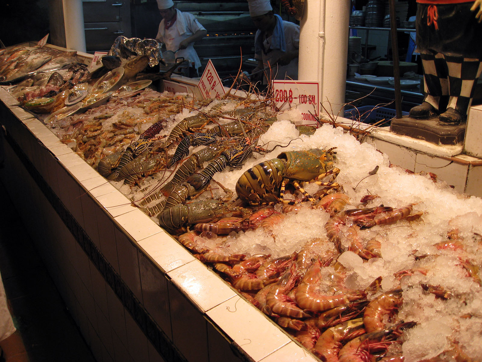 shrimp, lobsters and other seafood sit on ice in a shop