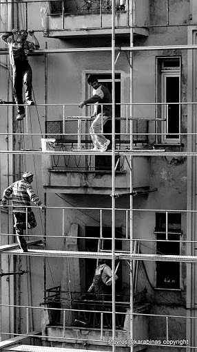 three people are hanging on scaffolding together
