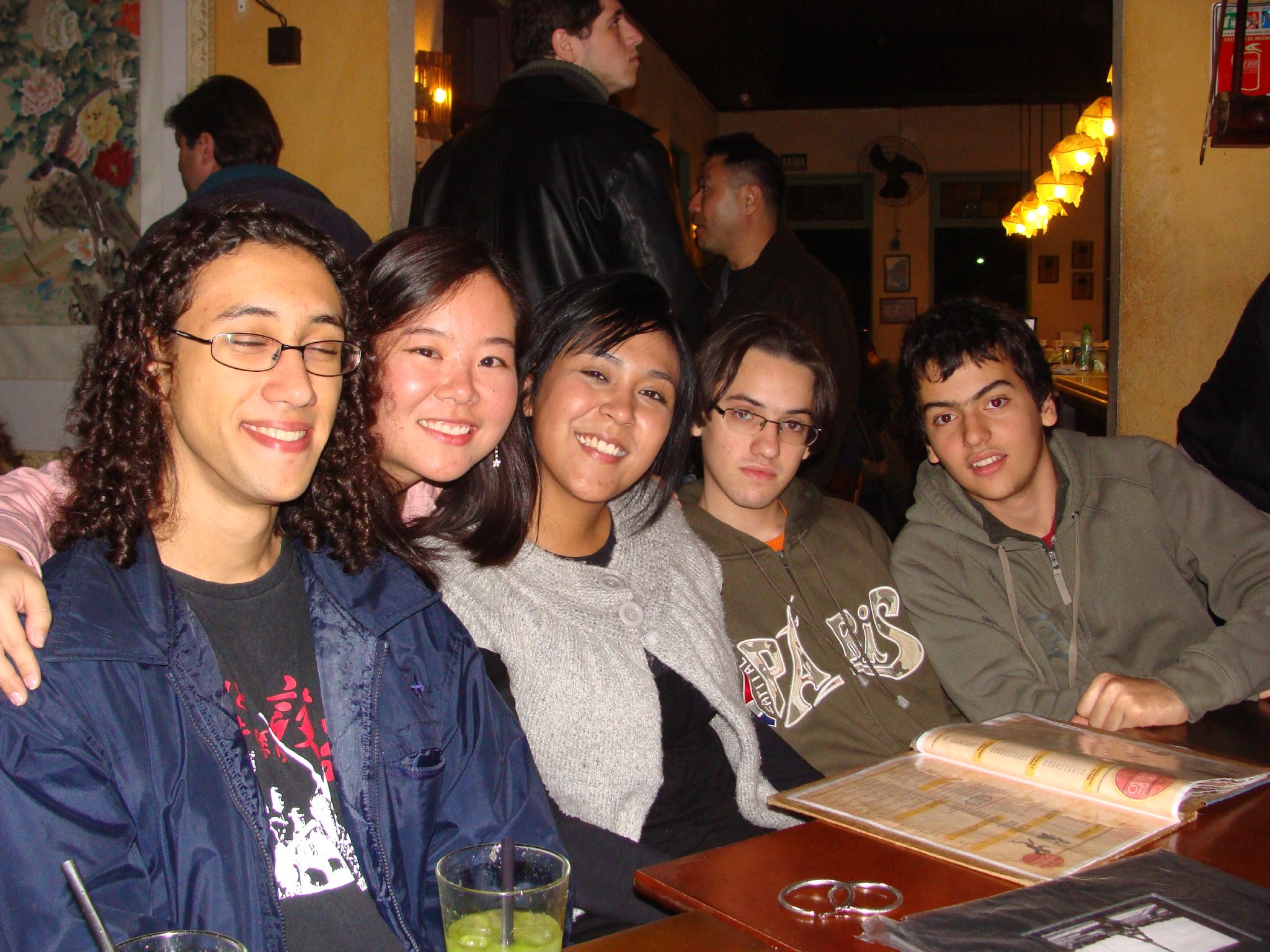 several people are sitting at a table in a bar smiling