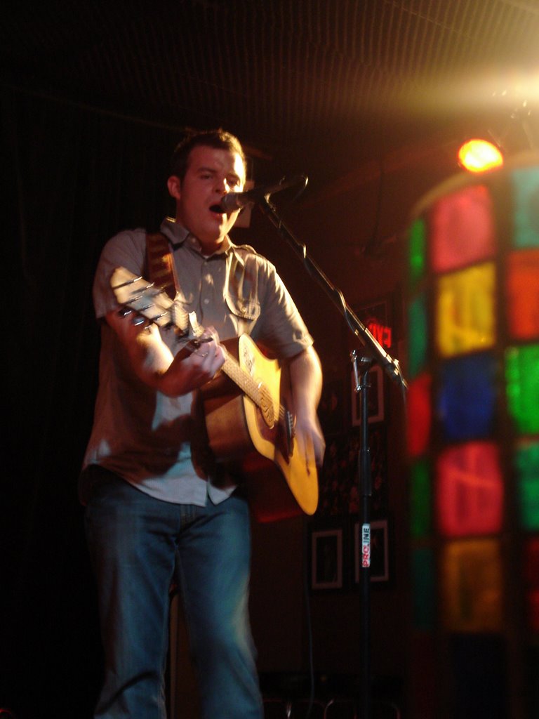 a man holding a guitar standing next to a microphone