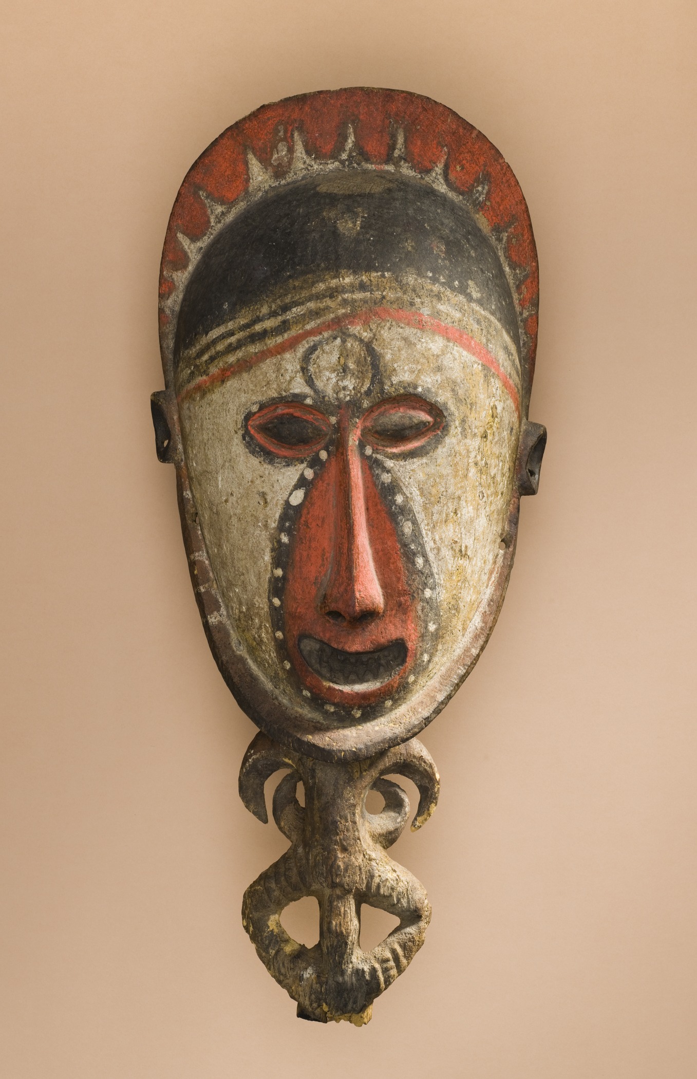 decorative mask hanging on wall against tan wall