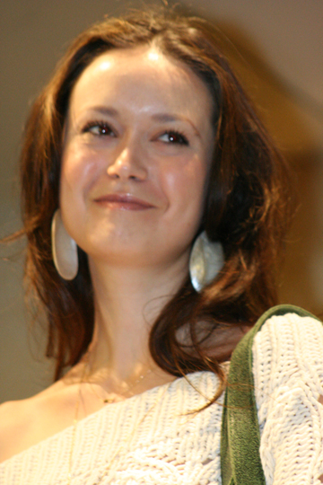 woman wearing white sweater and green necktie with silver earrings smiling