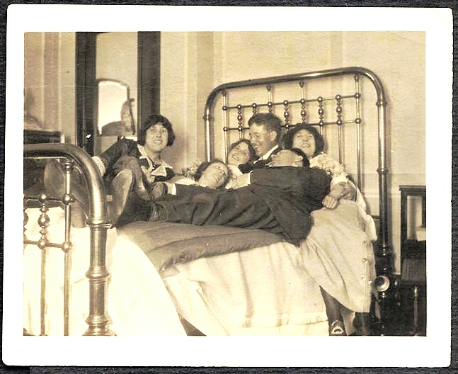 an old black and white po with several people in a bed