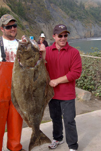 two men are standing next to each other holding up large fish