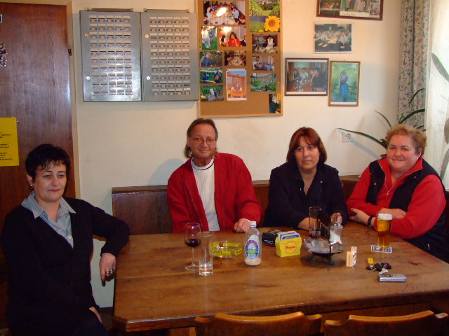 four people sitting around a table, with glasses on the top of it