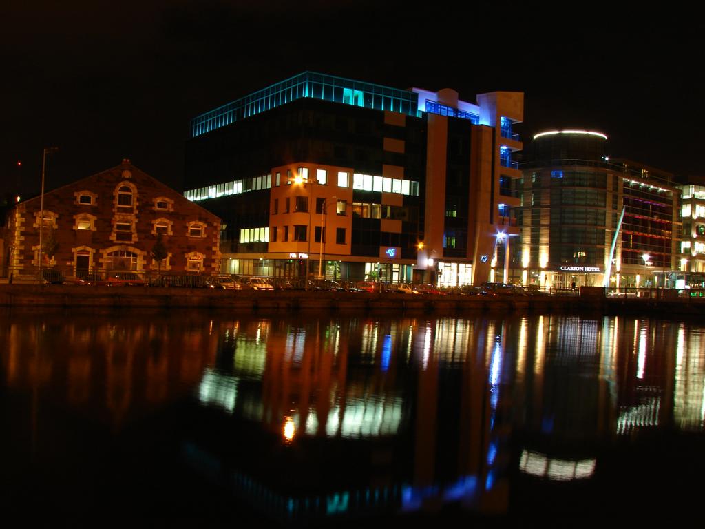 there are lights on the buildings at the river